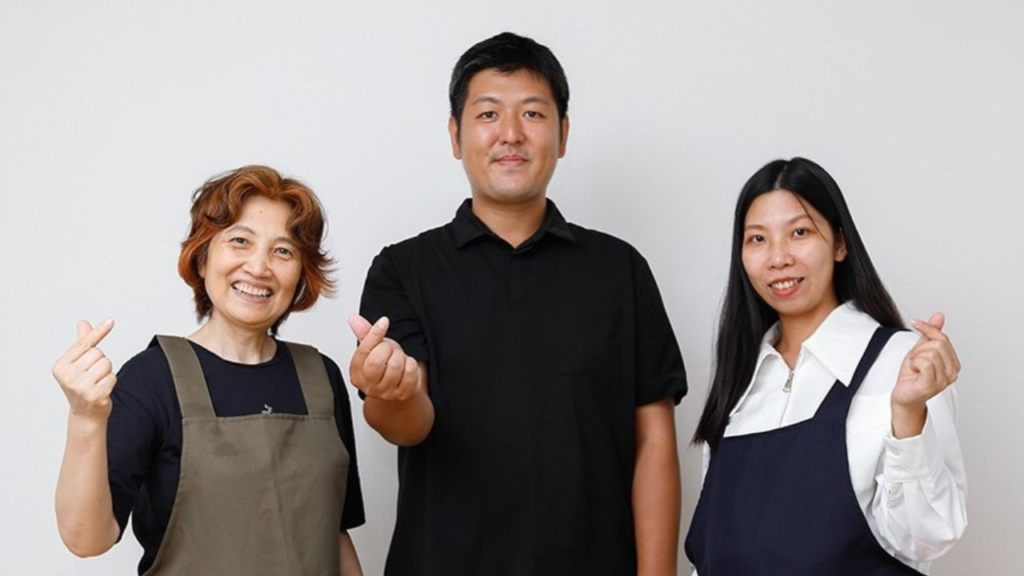 松谷さんとスタッフの方２名が笑顔でハートマークを作っています。
